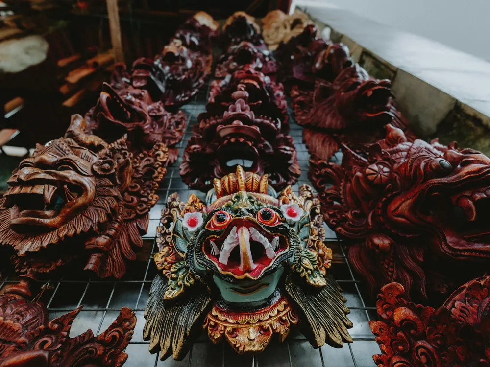 Carved and painted wooden masks laid out in rows