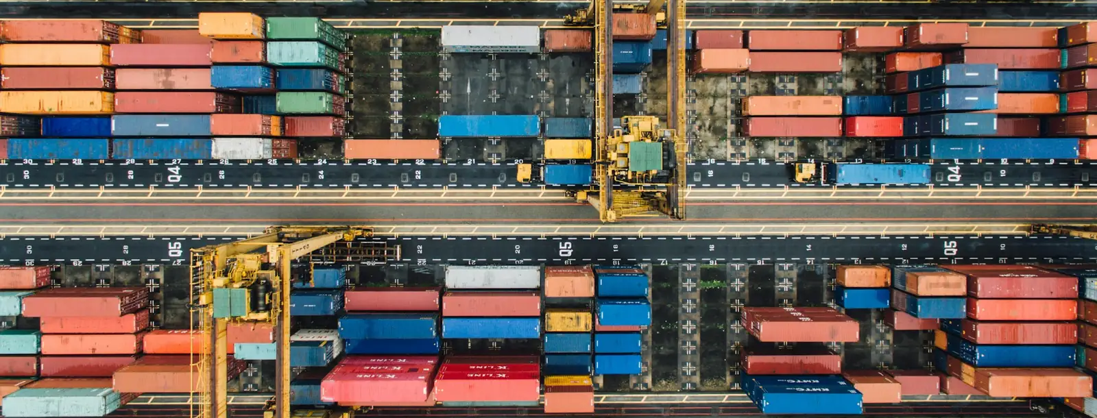 Aerial view of stacked shipping containers and gantry cranes in a container yard