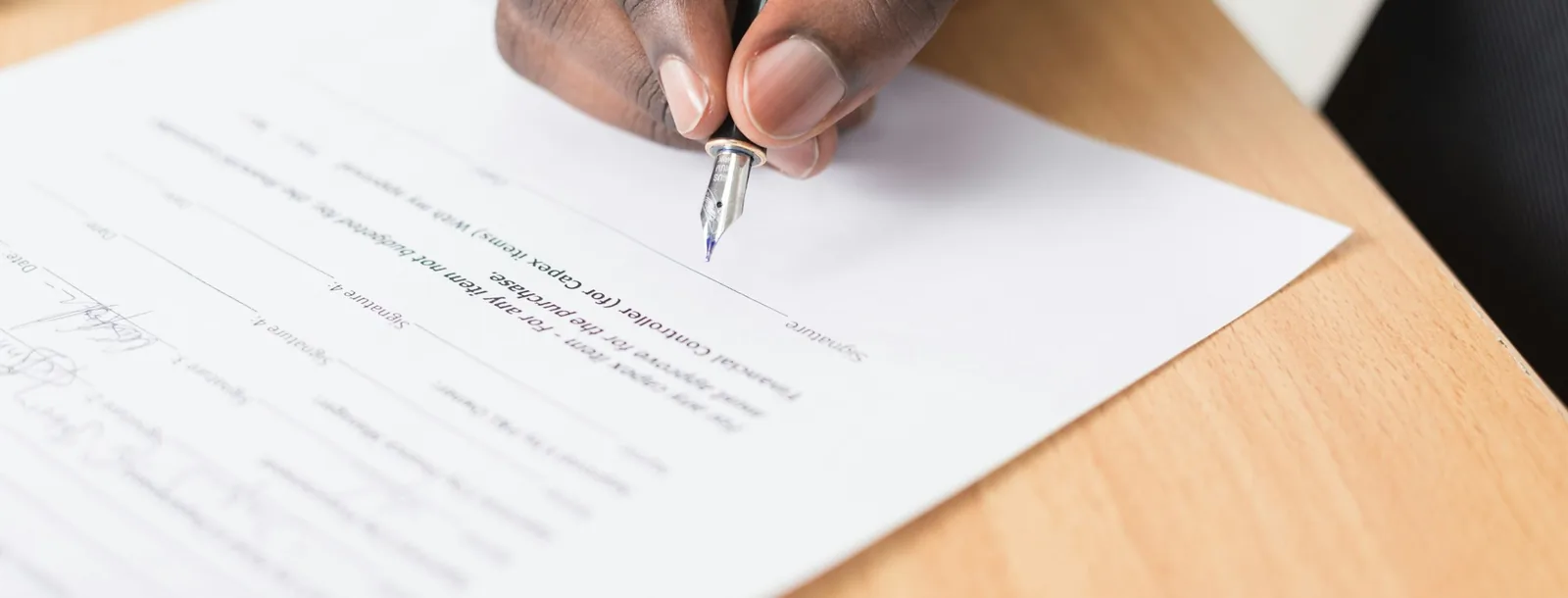 Hand signing a printed document at a desk