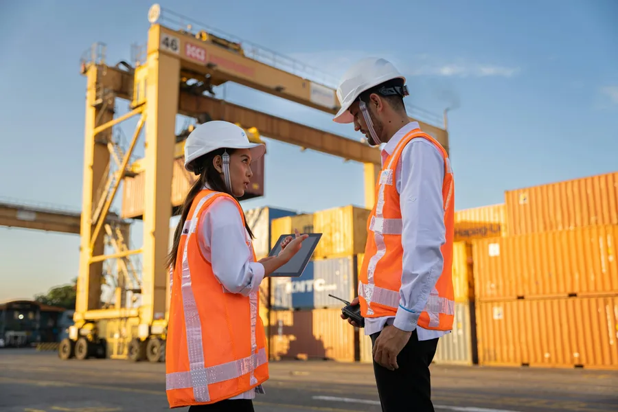 Two inspectors in hard hats at a container yard