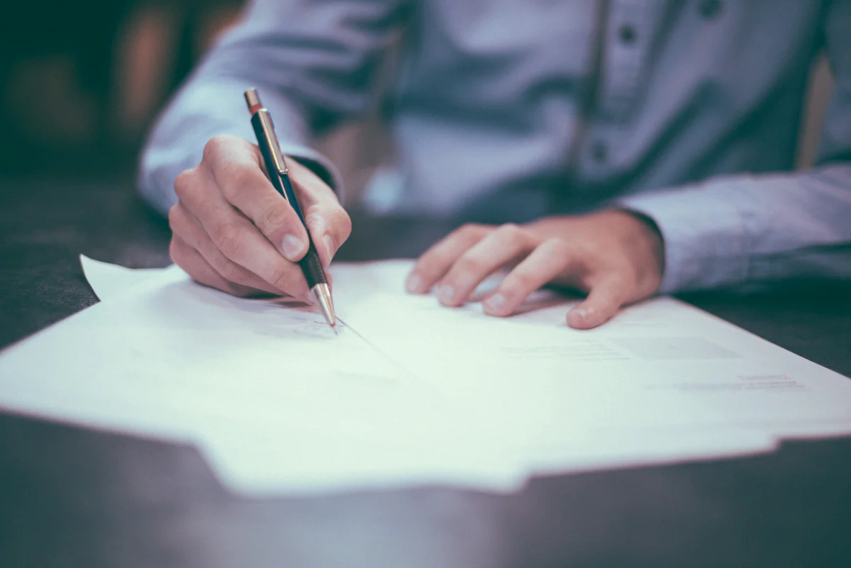 Hand signing a document at a desk