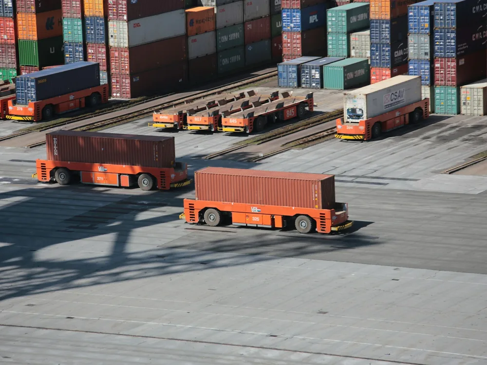Automated carriers moving containers across a terminal yard