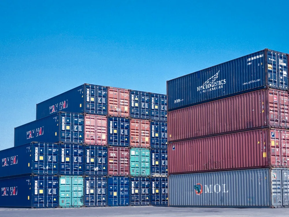 Stacked shipping containers under a blue sky