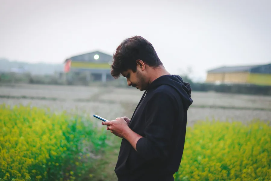 Man checking his phone in a farm field