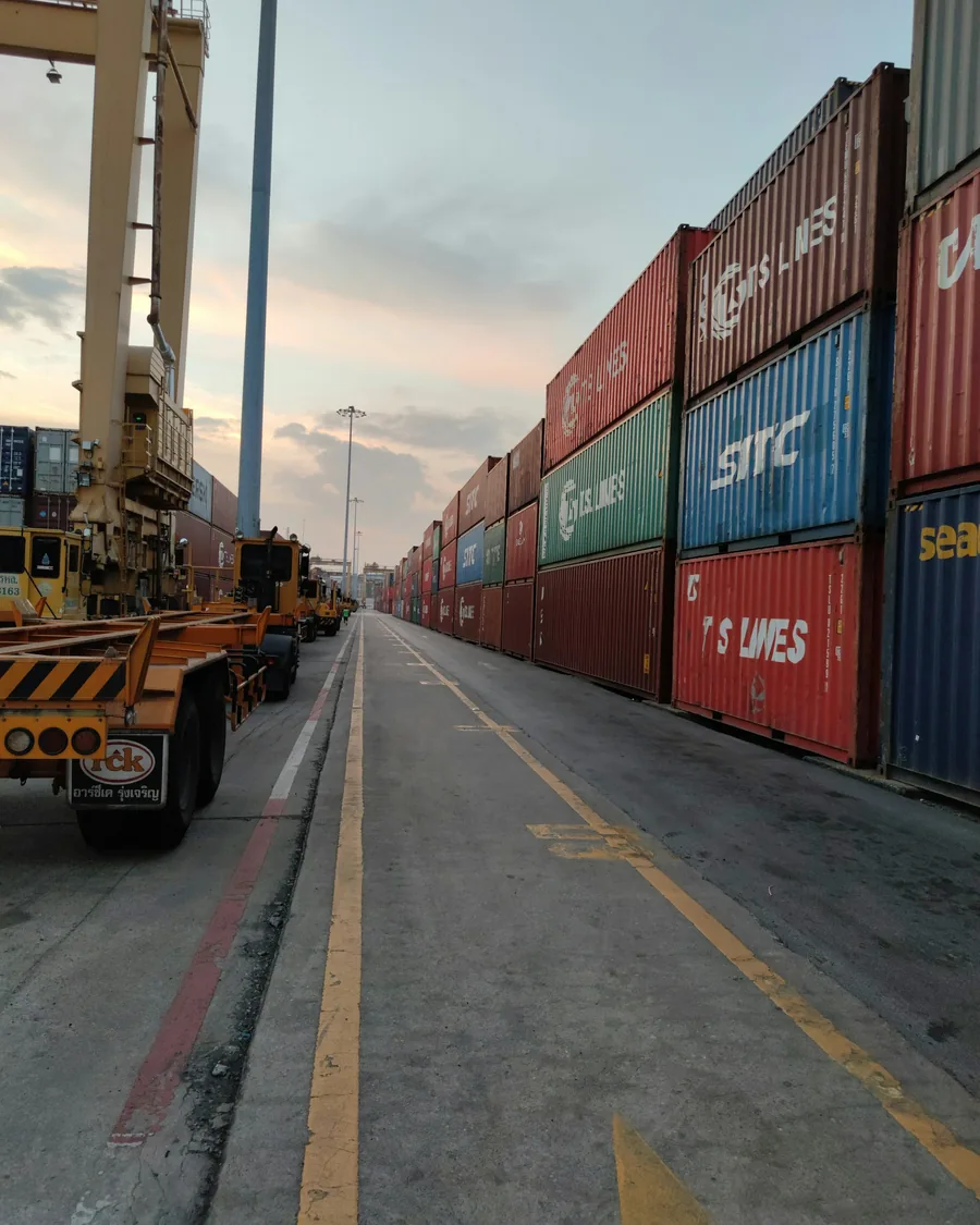 Stacked shipping containers lining a road inside a container terminal