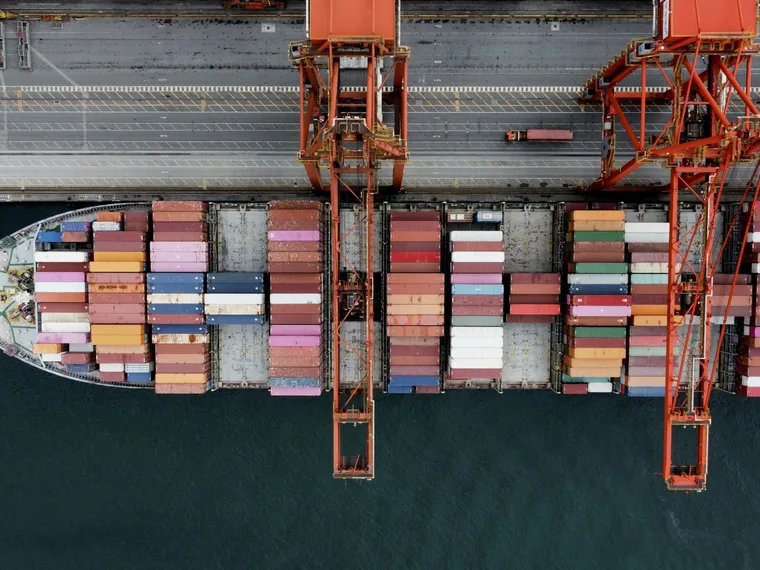 Aerial view of a container ship loaded with containers beside quay cranes