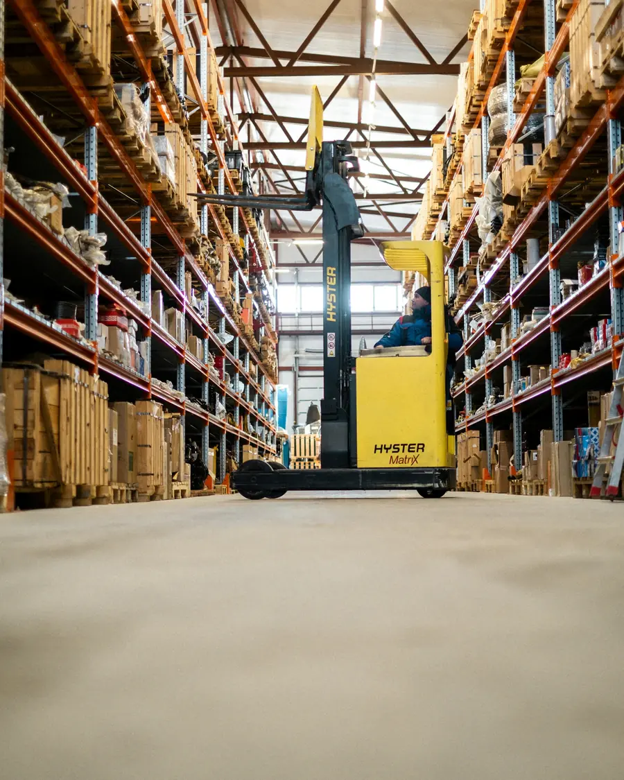 Reach truck in a warehouse aisle lined with racks of cartons