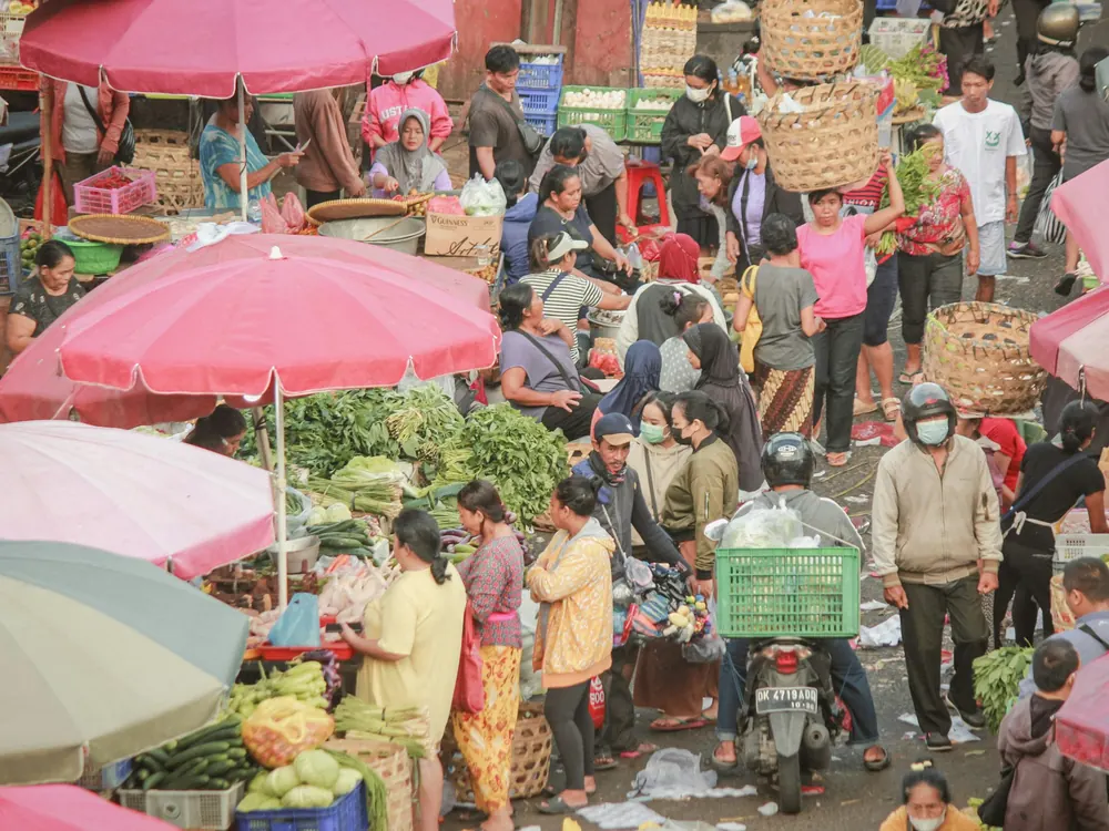 Busy street market with pink umbrellas and fresh produce