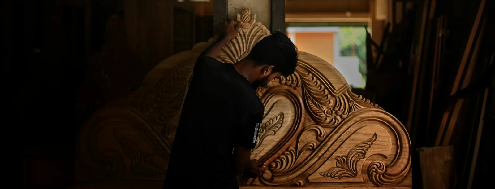 Craftsman working on a large carved wooden panel in a workshop