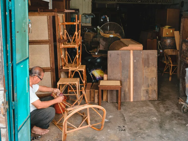 Craftsman assembling a chair frame among furniture in a workshop