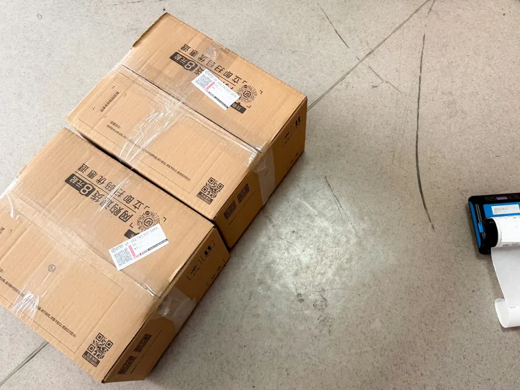 Taped cardboard boxes with labels next to a small label printer
