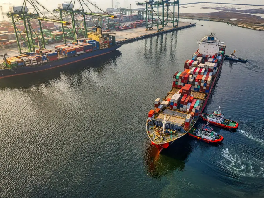 Container ship guided by tugboats near a port