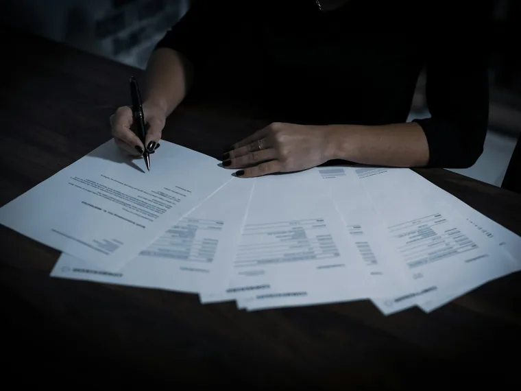Person signing a spread of printed documents