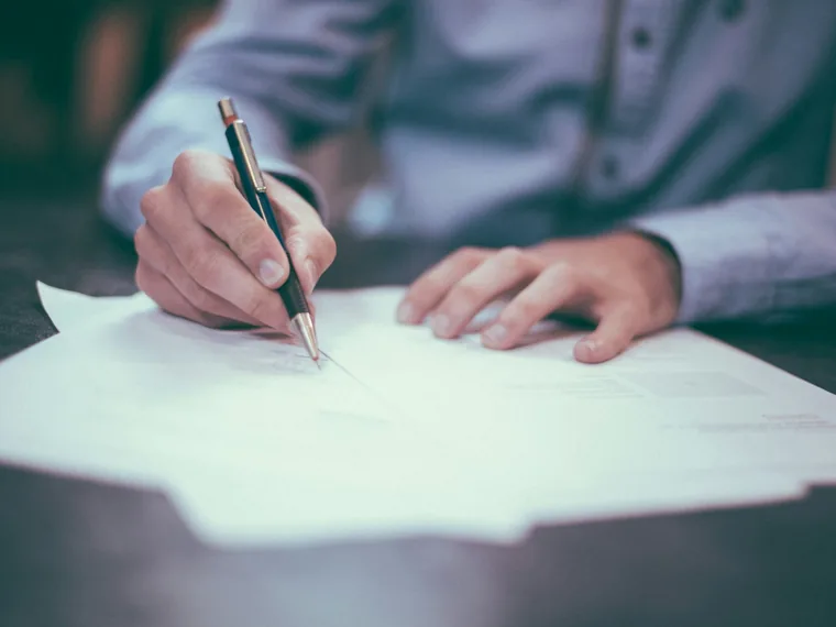 Hand signing a document with a pen